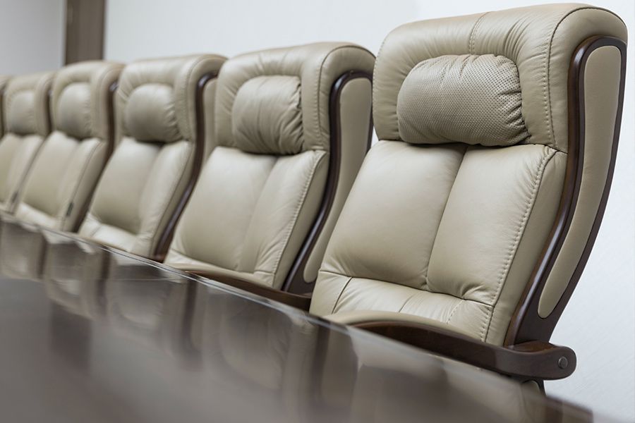 Leather chairs line a boardroom table, beige with dark wood trim.