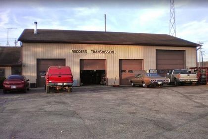 Wider's Transmission auto repair shop with garage doors open, vehicles parked outside, and a red truck.
