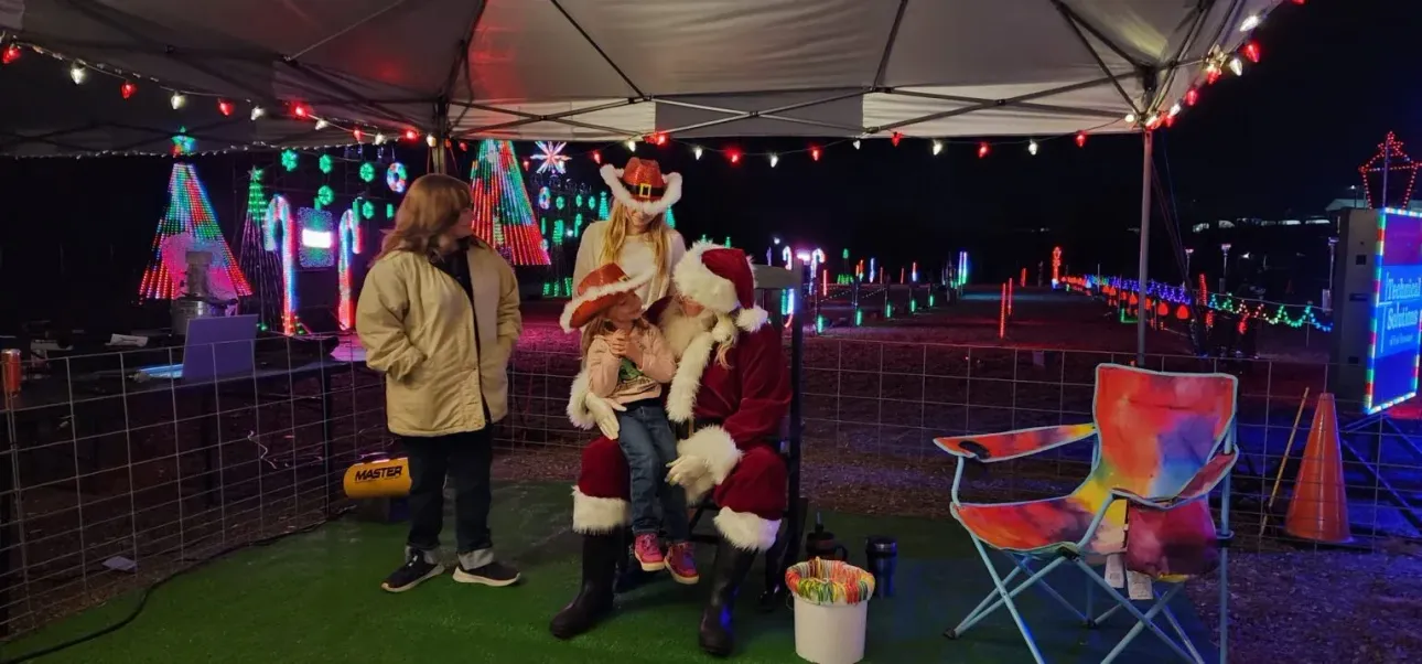 A group of people are standing under a tent with santa claus.
