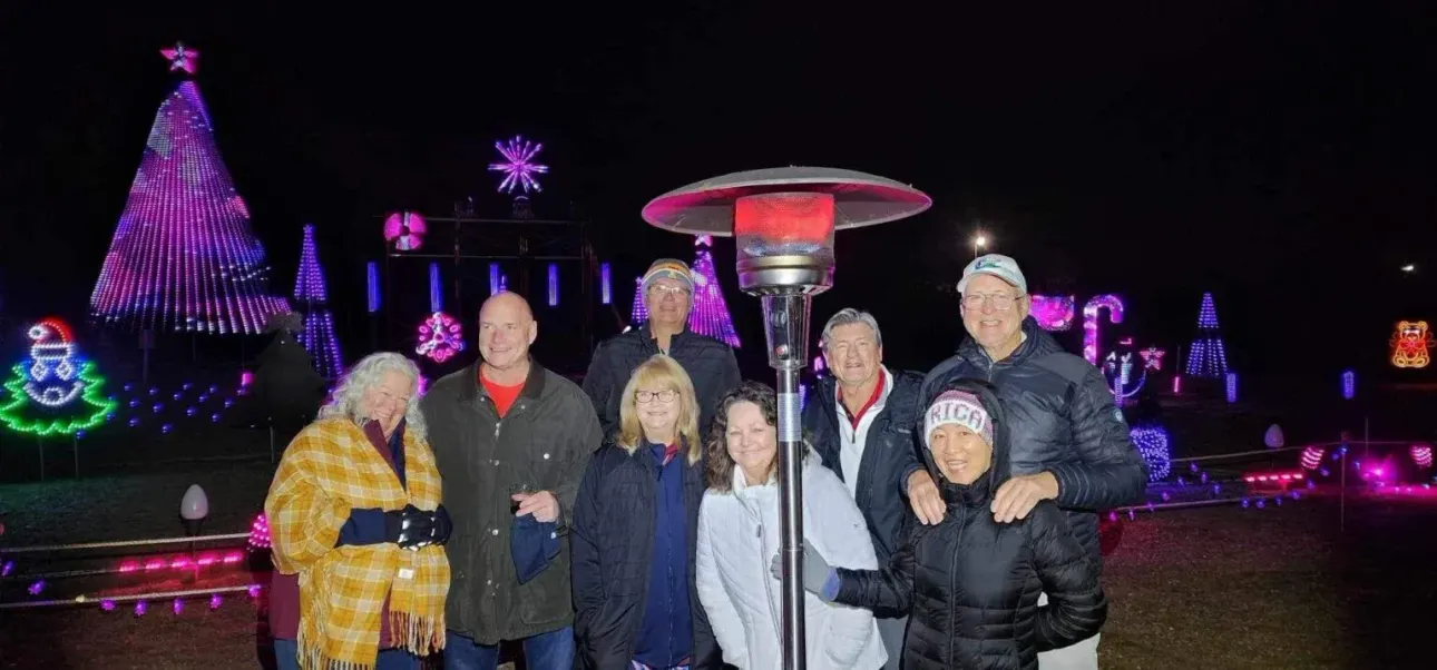 A group of people are posing for a picture in front of a christmas tree.
