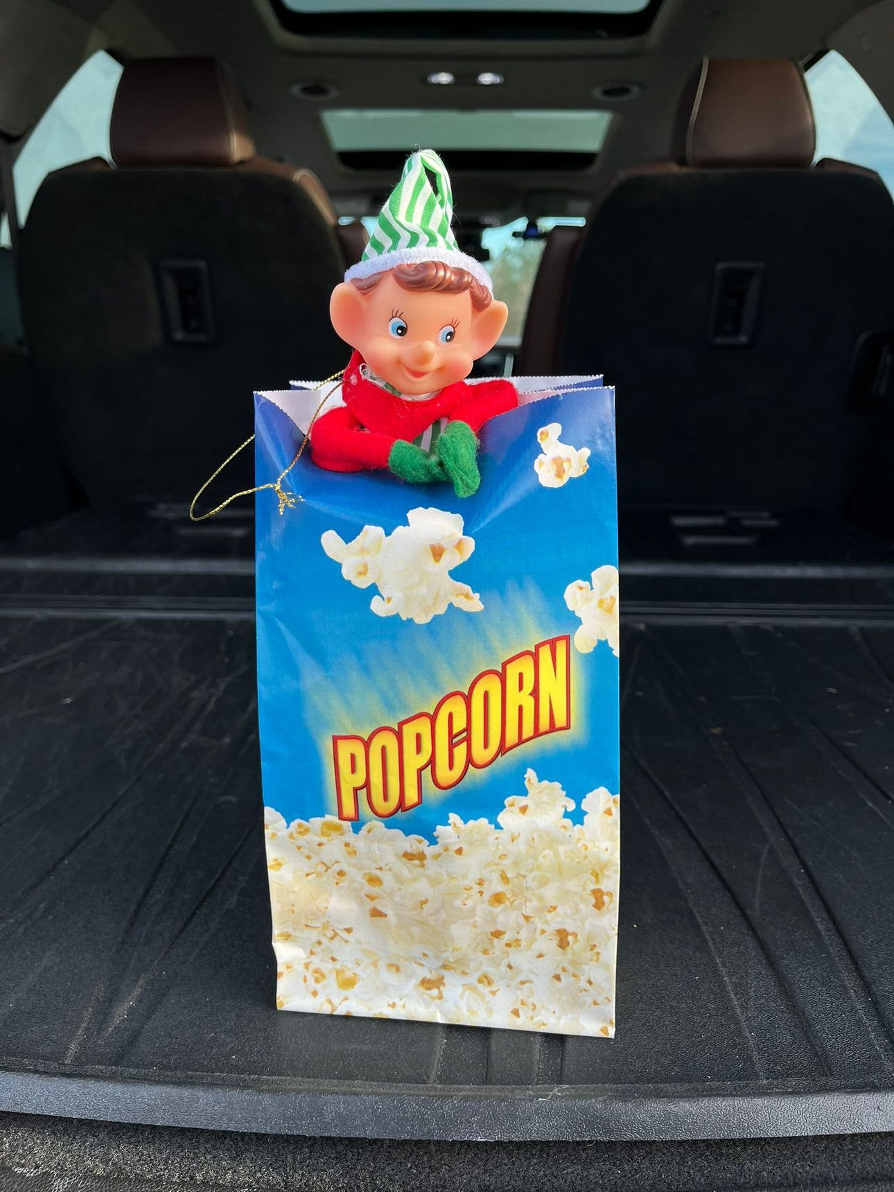 An elf on the shelf is sitting in a bag of popcorn