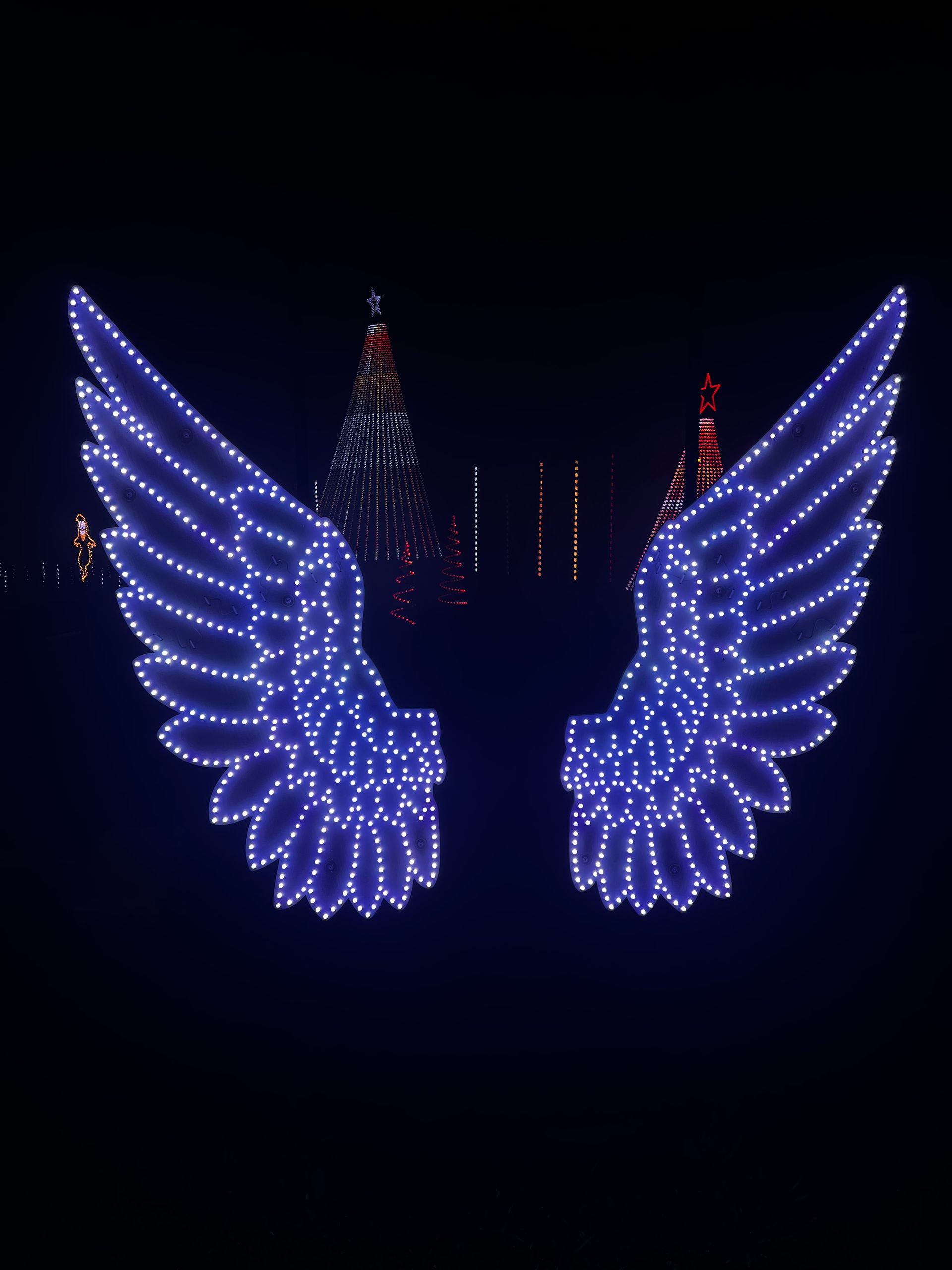 A pair of blue angel wings with a christmas tree in the background