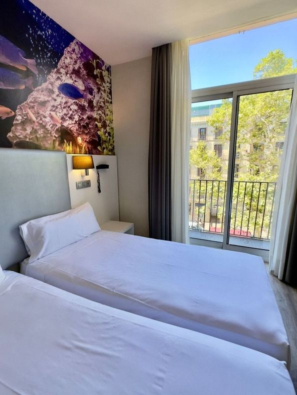 A hotel room with two beds and a balcony