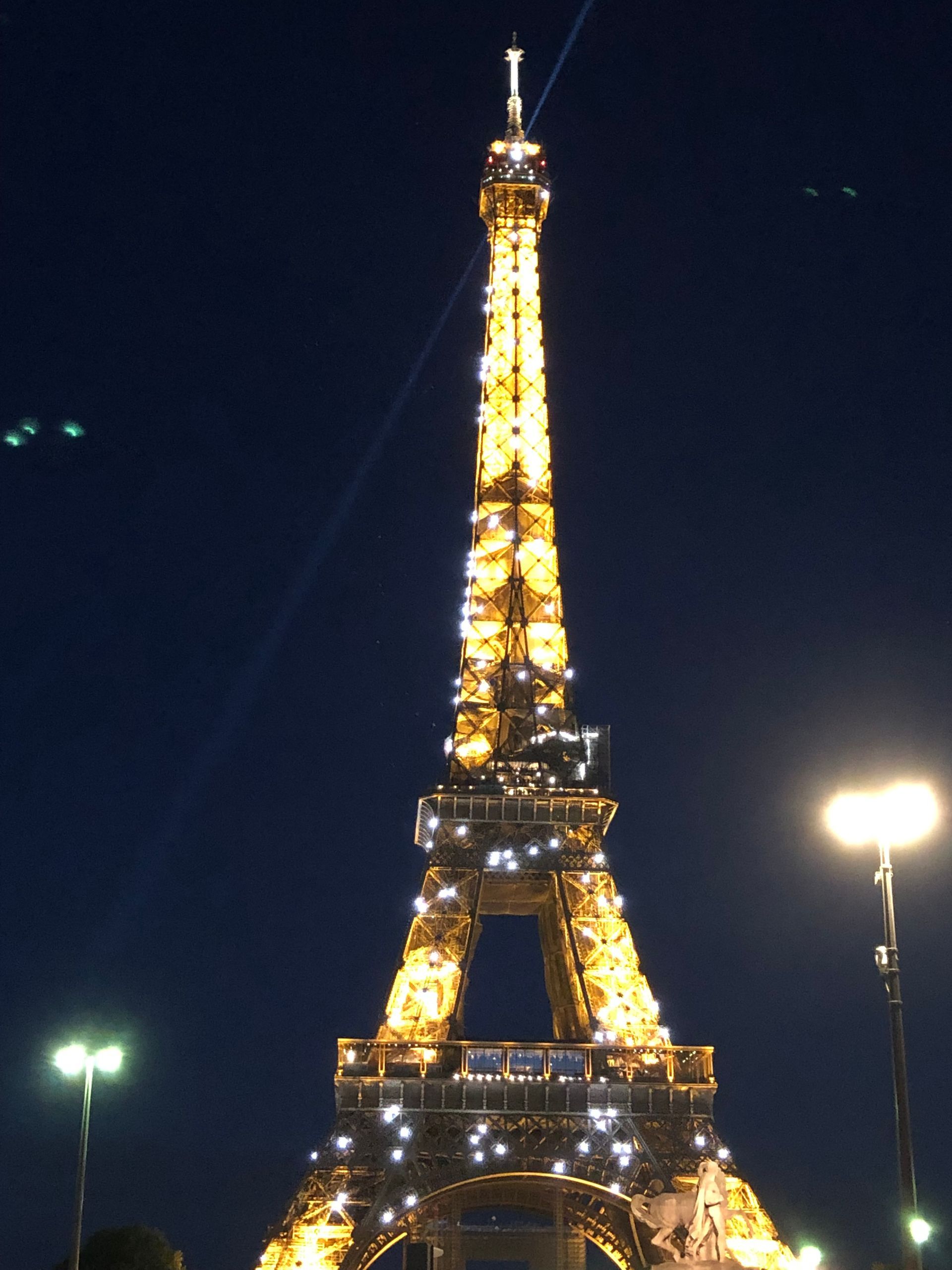 The Eiffel Tower at night, glowing with golden lights against a dark sky.
