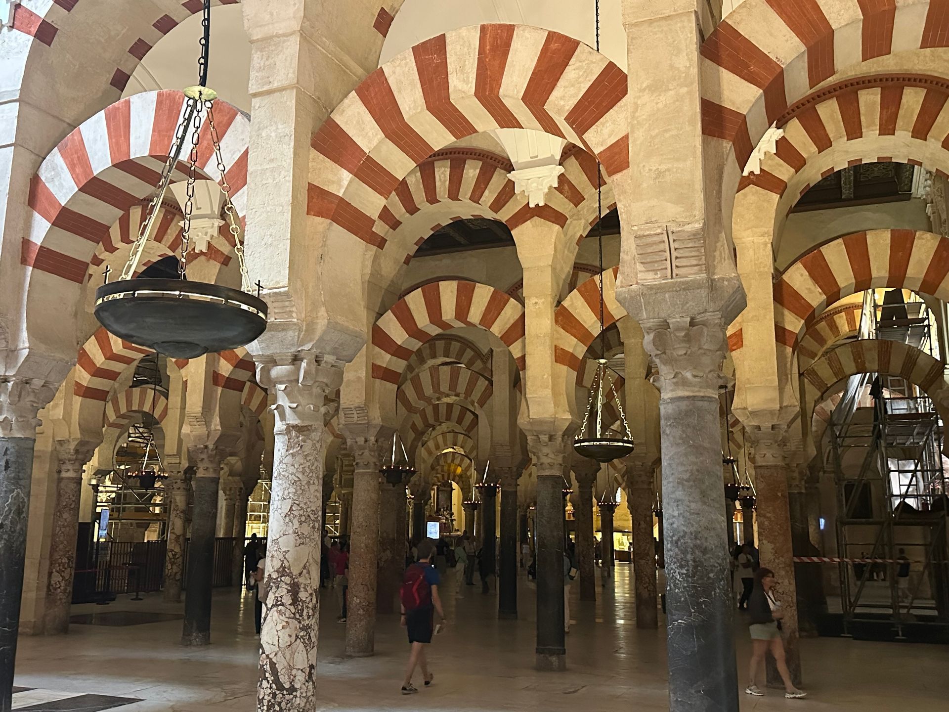 Ornate interior with rows of double arches featuring alternating red and white stones, supported by marble columns.