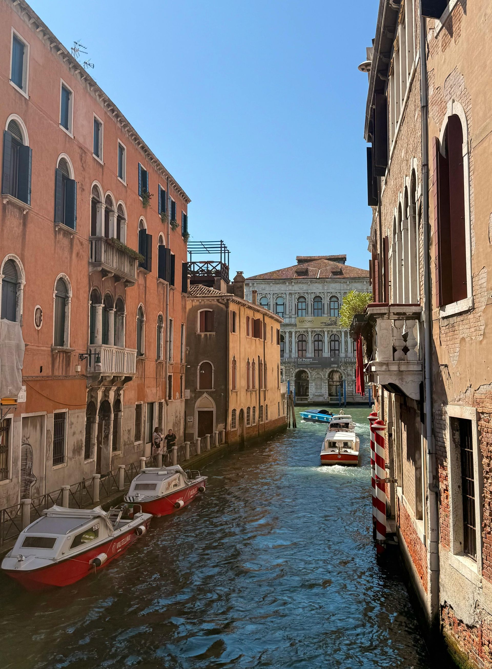 Venice canal with boats between colorful buildings on a sunny day