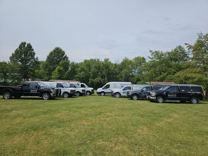 A row of trucks and vans are parked in a grassy field.