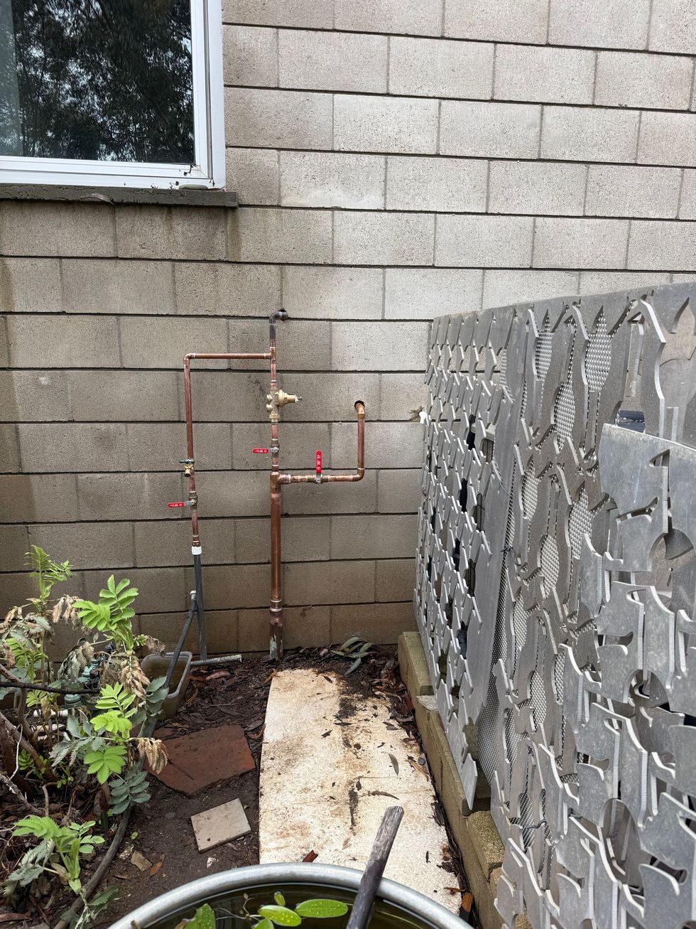 Air conditioning units with toolbox and gloves in backyard.