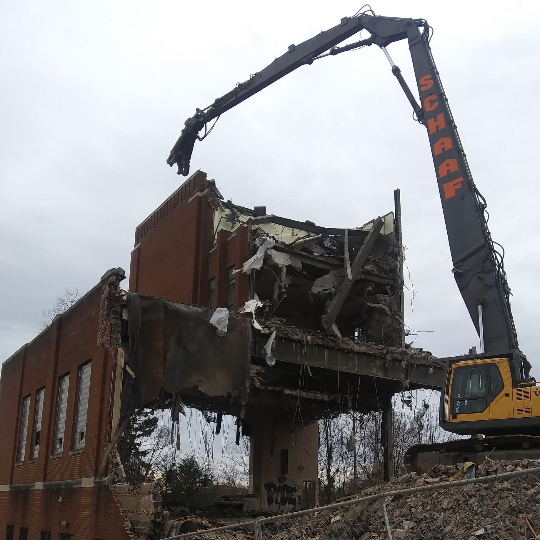 Old industrial building being demolished with high reach excavator