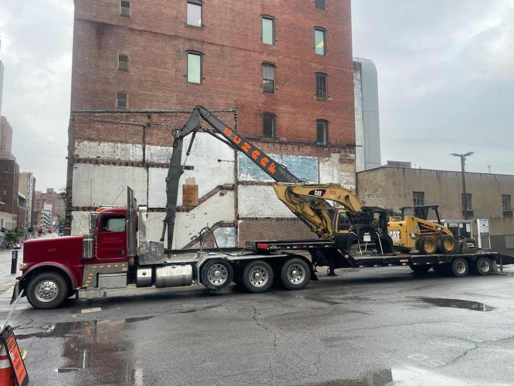 high reach excavator being hauled on a large tractor trailer