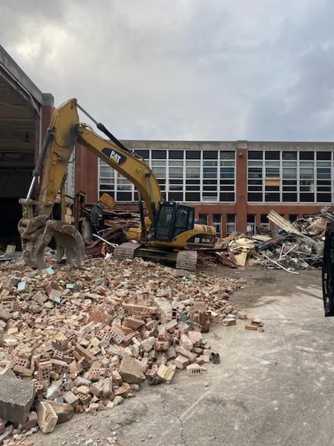 excavator cleaning up brick from a demolition job