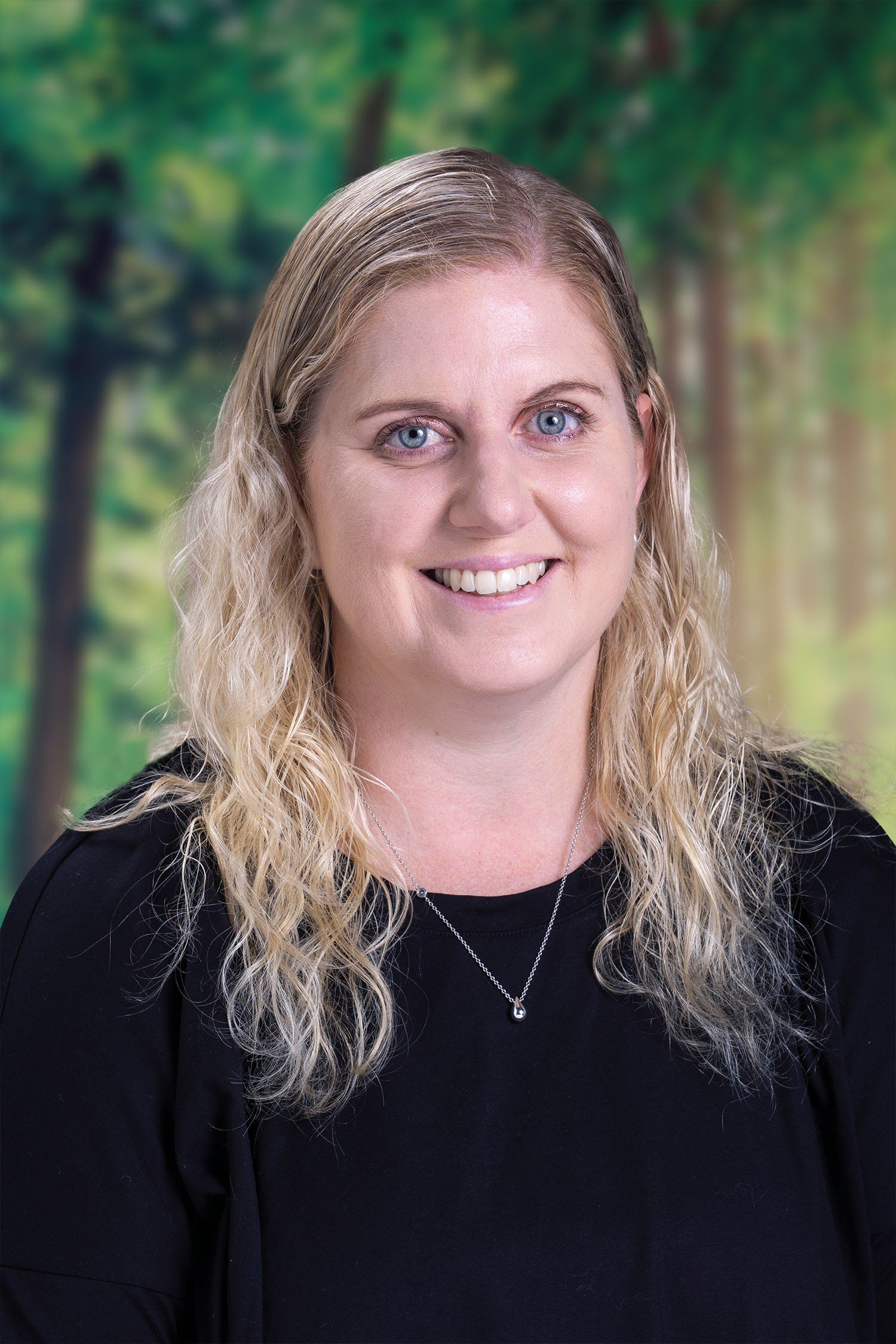 A woman with long blonde hair and blue eyes is smiling for a picture.