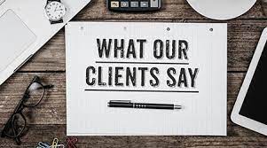 A piece of paper with the words `` what our clients say '' written on it is on a wooden table.