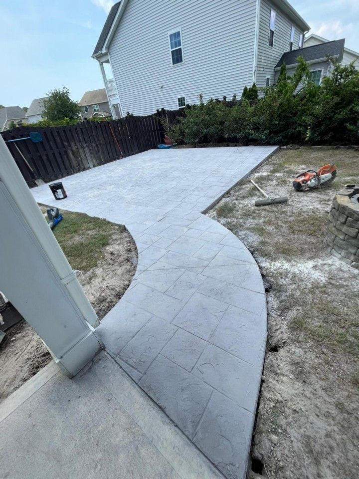 A concrete walkway is being built in the backyard of a house.