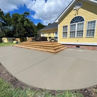 A yellow house with a concrete patio in front of it.