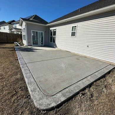 A concrete patio is being built in front of a house.