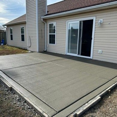 A concrete patio in front of a house with a sliding glass door.