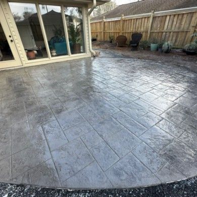 A stamped concrete patio with a wooden fence in the background.