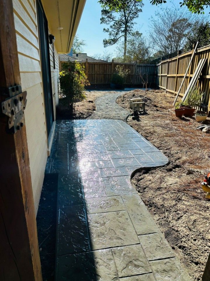 A concrete walkway is being built in the backyard of a house.