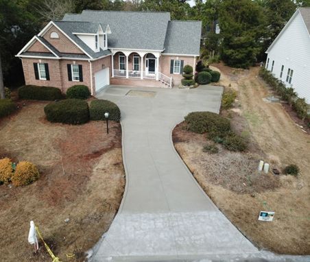 An aerial view of a house with a concrete driveway leading to it.