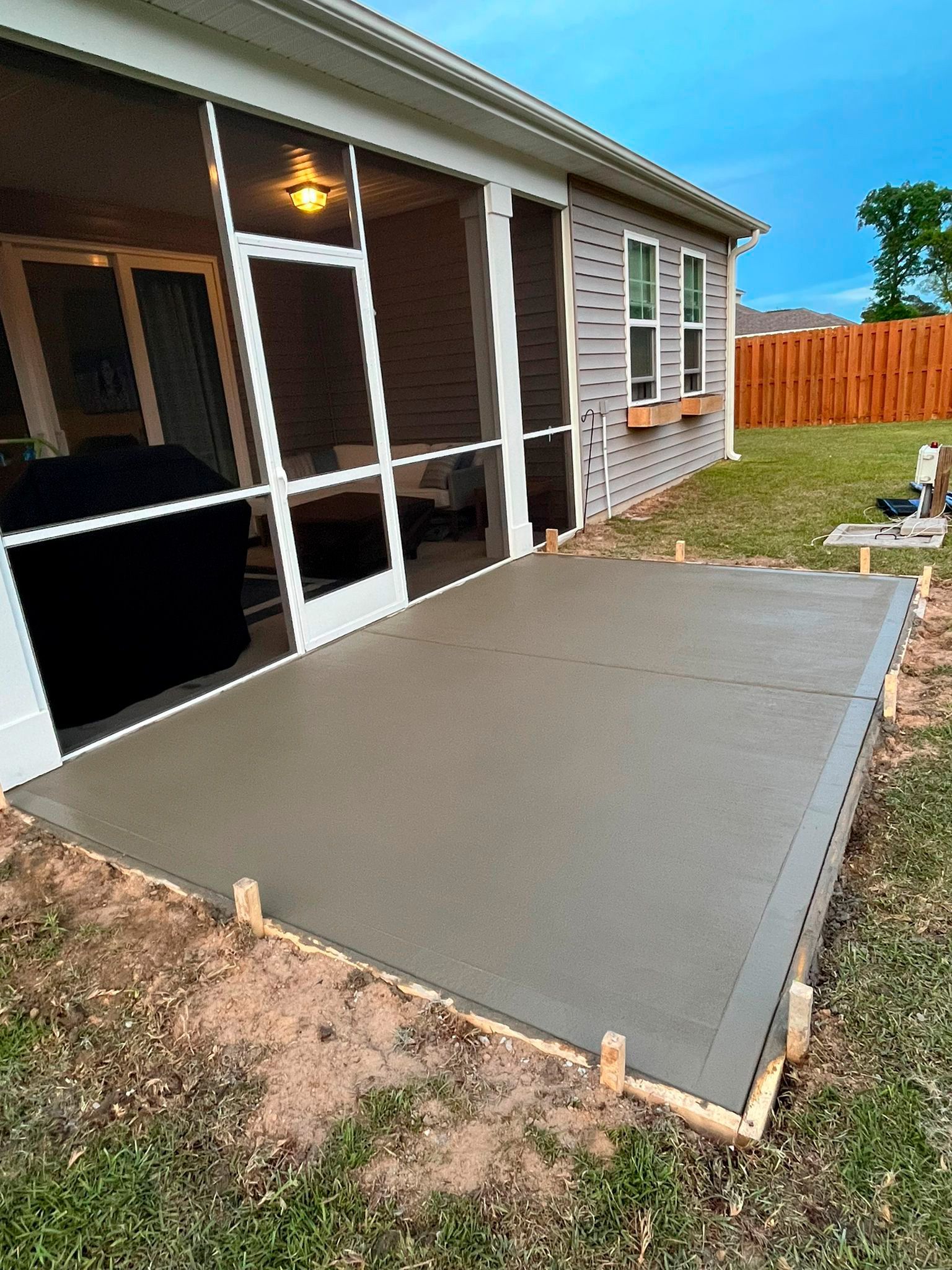 A concrete patio is being built in front of a screened in porch.