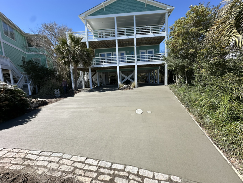 An aerial view of a house with a concrete driveway leading to it.