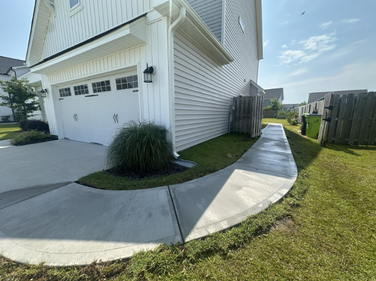 A concrete walkway is being built in the backyard of a house.