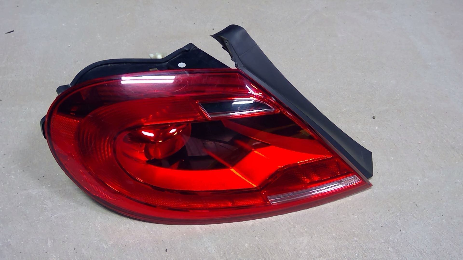 A red car taillight assembly isolated on a plain, light gray background.