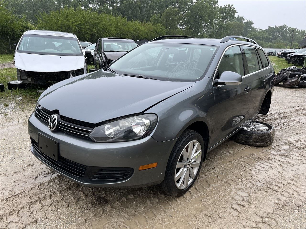 A tan metal-sided industrial building with a brick facade and a gravel parking lot under a clear blue sky.