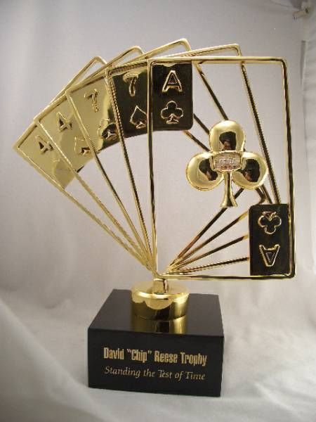 a gold trophy with playing cards and a clover on it
