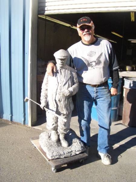 a man standing next to a statue of a man holding a golf club