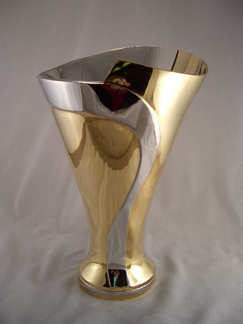 a gold and silver vase is sitting on a white cloth