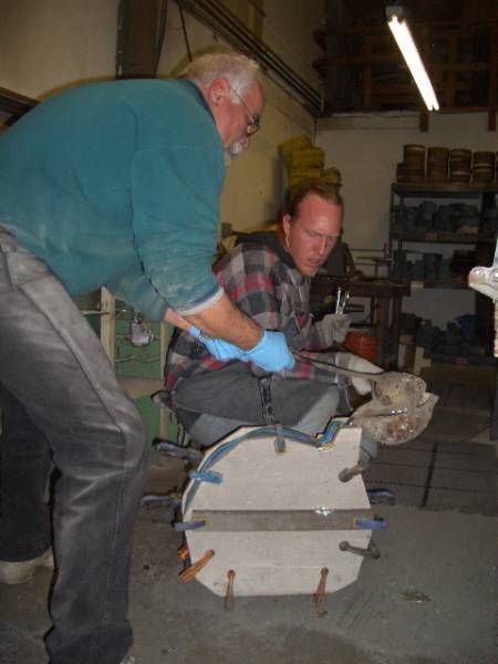 two men are working on a piece of metal in a workshop