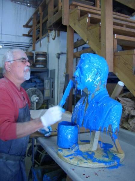 a man is painting a blue statue of a man