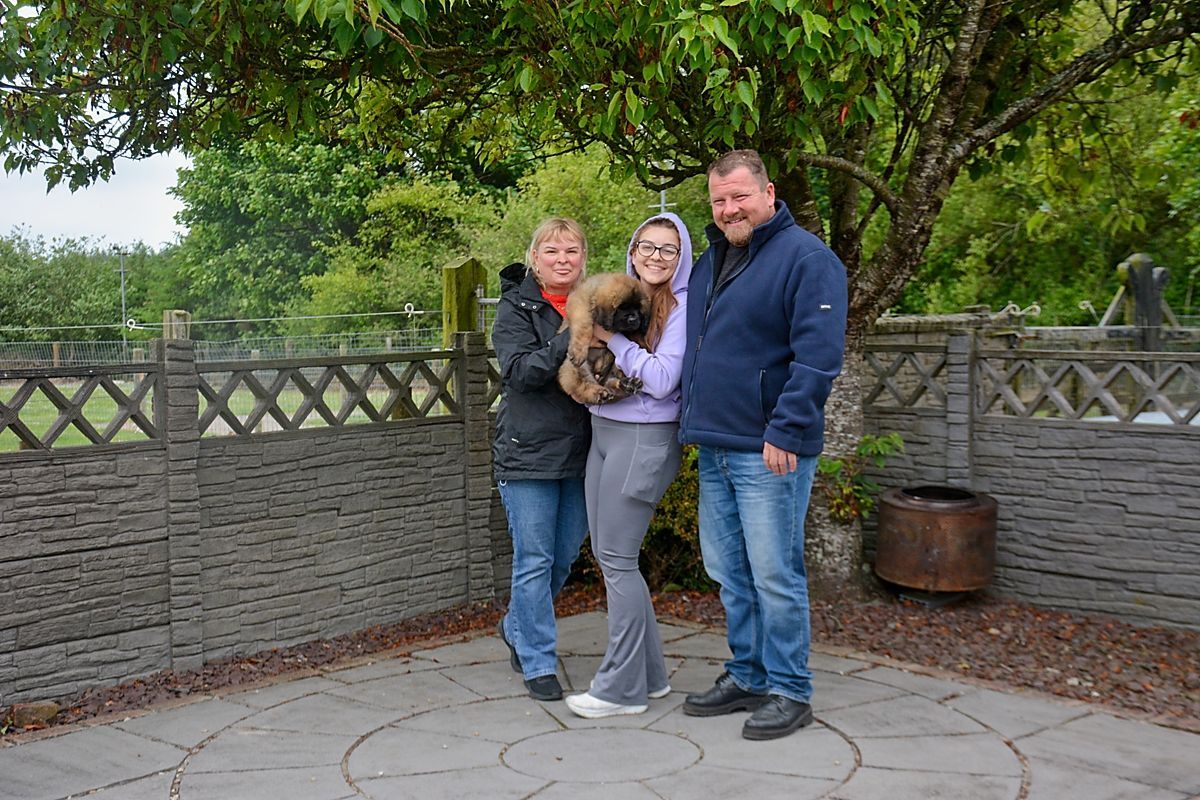 Family standing outside with a puppy, smiling.
