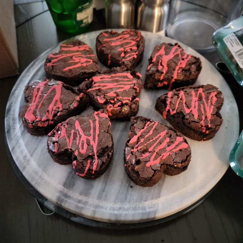 A plate of heart shaped brownies with pink frosting