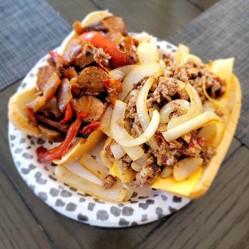 A paper plate topped with a sandwich filled with meat and cheese