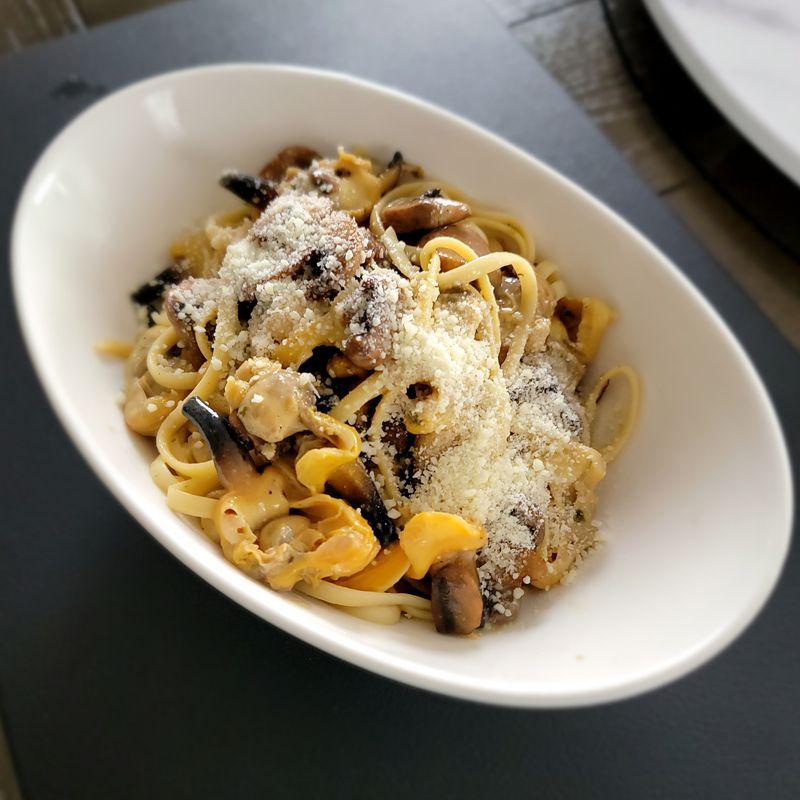 A bowl of pasta with mushrooms and cheese on a table