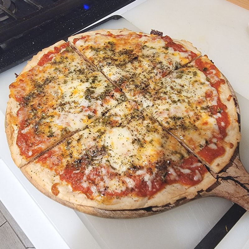 A pizza with tomato sauce and cheese on a wooden cutting board