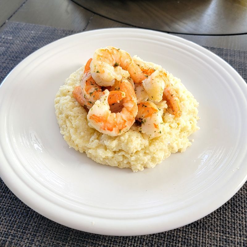 A white plate topped with shrimp and grits