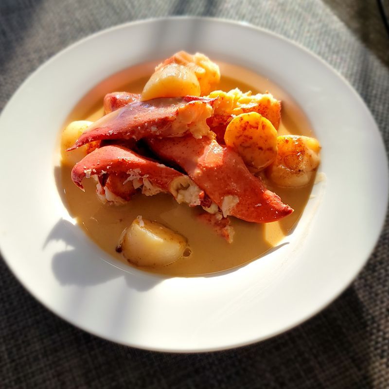 A white plate topped with lobster and potatoes