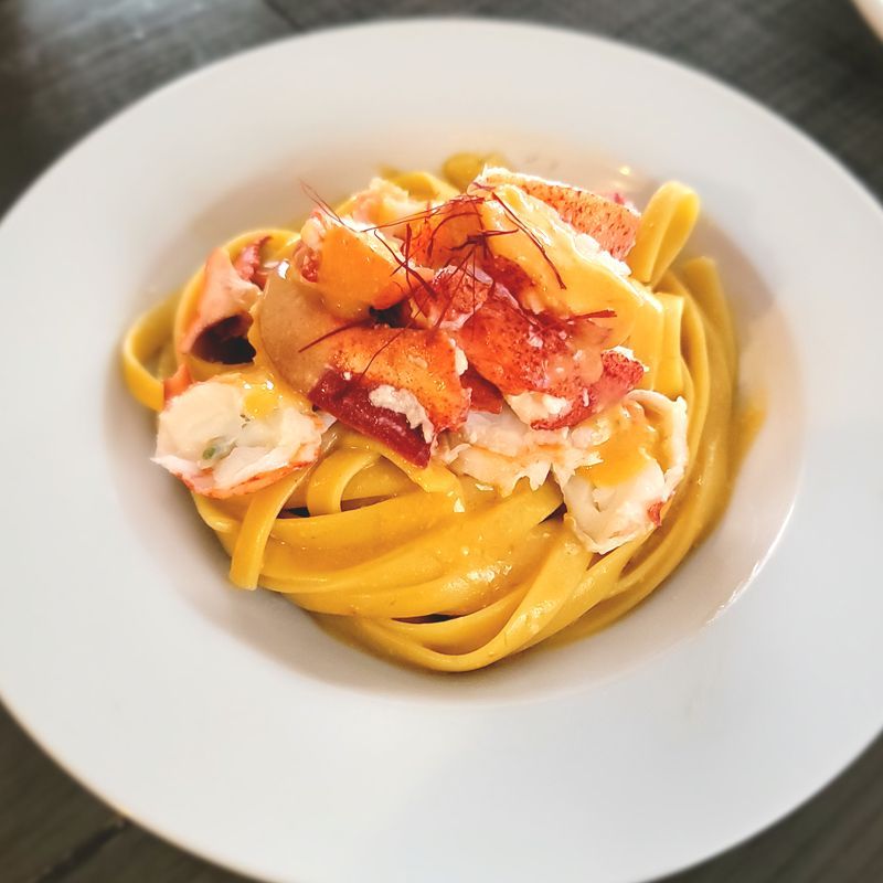 A white plate topped with noodles and lobster