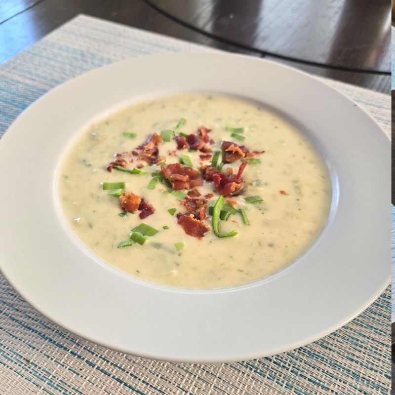 A bowl of potato soup with bacon and green onions on top