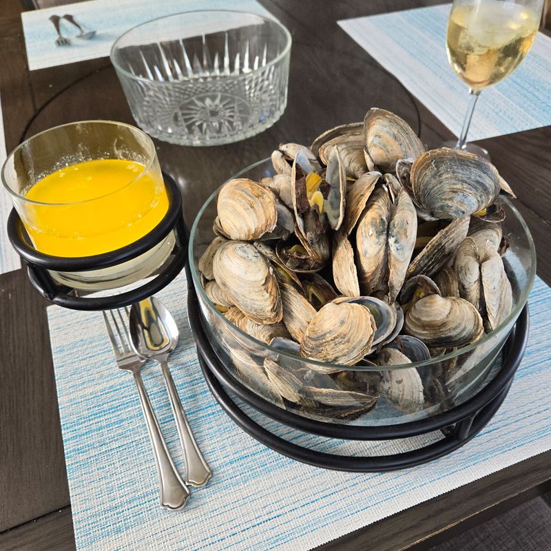 A bowl of clams sits on a table next to a glass of orange juice.