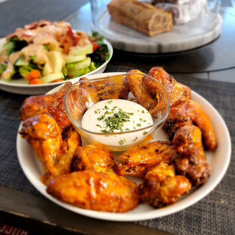 A plate of chicken wings with ranch dressing on a table