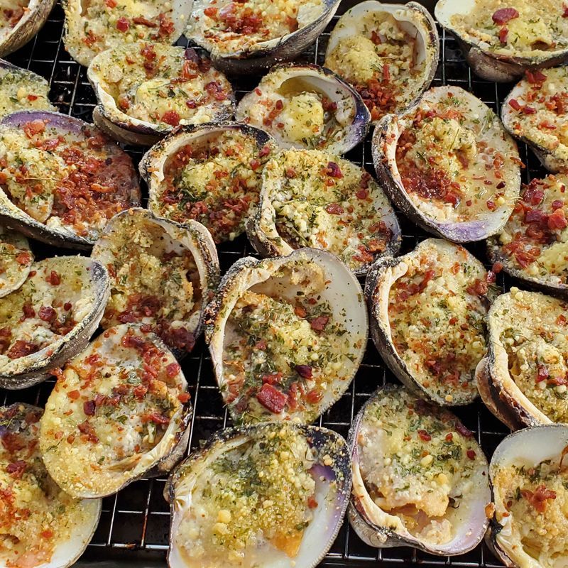 A bunch of stuffed clams are sitting on a cooling rack.