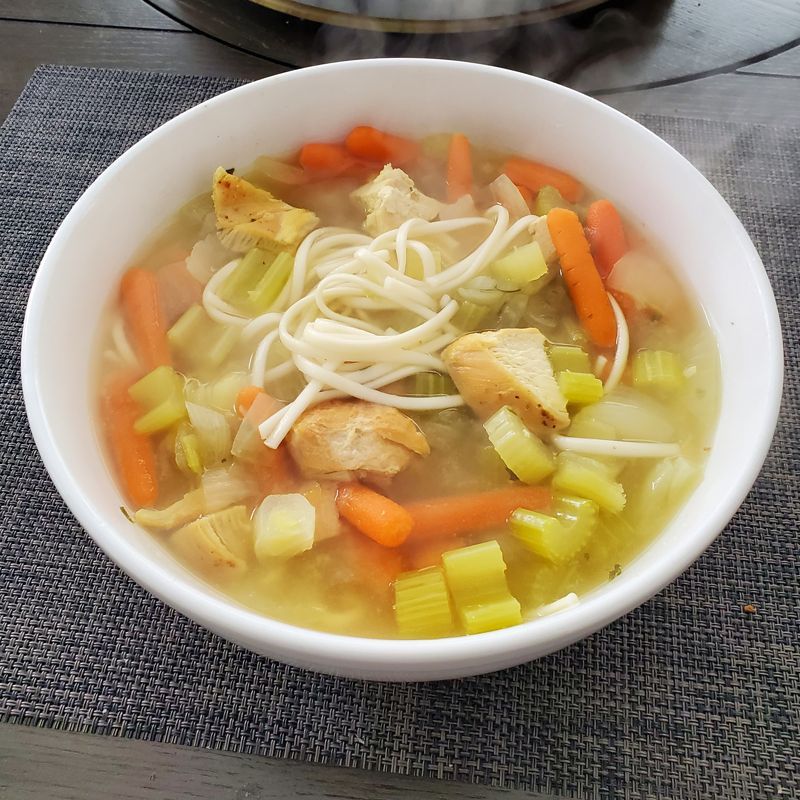 A bowl of chicken noodle soup with carrots and celery