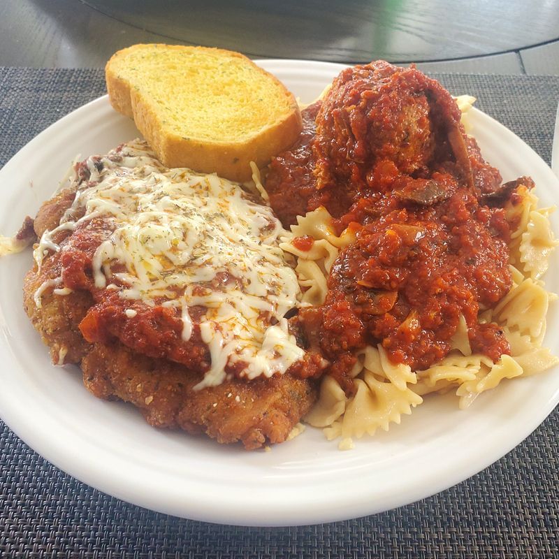 A white plate topped with pasta meatballs and garlic bread