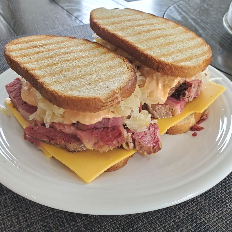 A corned beef sandwich with meat and cheese on a white plate