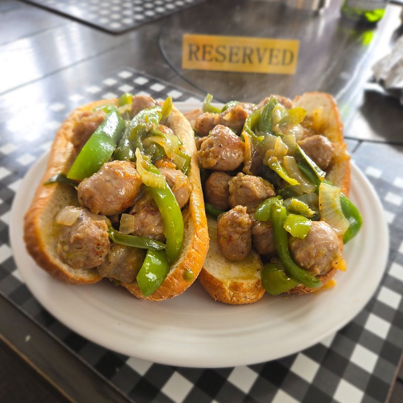 A plate of sausage and peppers with a reserved sign in the background